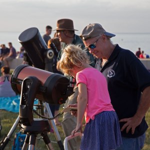 Photo: Girl views Sun through a CAA member's telescope. Photo by James Guilford.